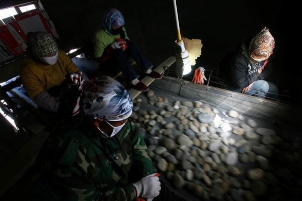 在和田市郊的一个砂石料厂，工人正在砂石料的传输带下挑玉石